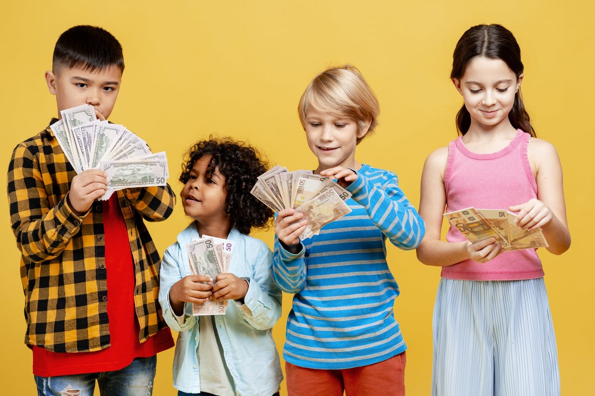 Young diverse children holding cash banknotes, learning about money, savings, and investments
